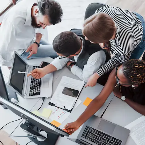 Equipe reunida trabalhando com computadores no escritório.